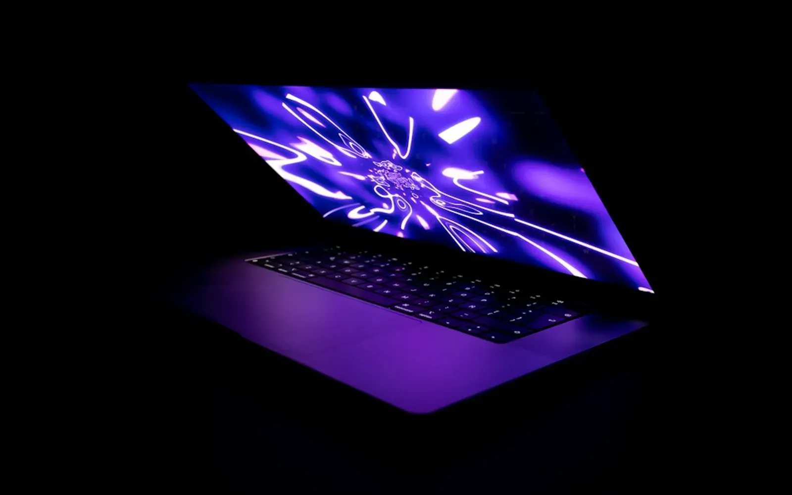 Aufgeklappter Laptop mit violett leuchtendem Bildschirm im dunklen Raum – Sexchat sicher nutzen