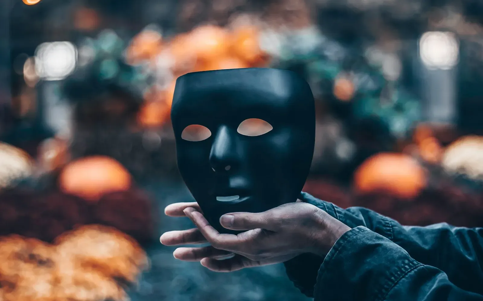 Hand hält eine schwarze Maske vor unscharfem Hintergrund – Sexchat Nickname Ideen