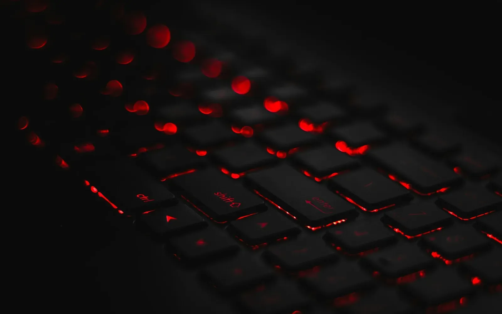 Laptop-Tastatur mit roter Hintergrundbeleuchtung im Dunkeln – Cybersex im Chat