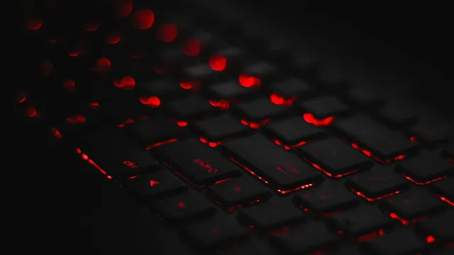 Laptop-Tastatur mit roter Hintergrundbeleuchtung im Dunkeln – Cybersex im Chat